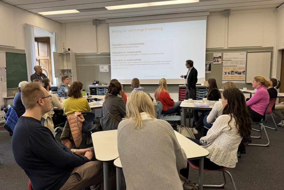 Prof. Dr. Andreas Eberth (stehend rechts) erläutert den Teilnehmenden wichtige Punkte einer Bildung für nachhaltige Entwicklung. Stehend links im Bild: Dr. Hannes Birnkammerer; Foto: Universität Passau