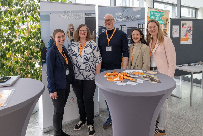 Vier Mitarbeiterinnen und ein Mitarbeiter des Zentrums f&uuml;r Lehrkr&auml;ftebildung und Fachdidaktik stehen an einem Stehtisch, auf dem Infomaterial liegt. Hinter den Personen stehen Info-Banner und -Aufsteller.