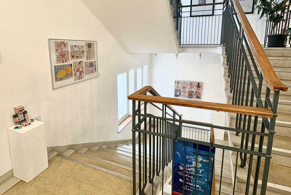 Ein Einblick in die Vernissage des ZLF. Zu sehen sind einige der Ausstellungsst&uuml;cke des Kunstwettbewerbs, verteilt im Treppenhaus des Institutsgeb&auml;udes der Uni Passau.