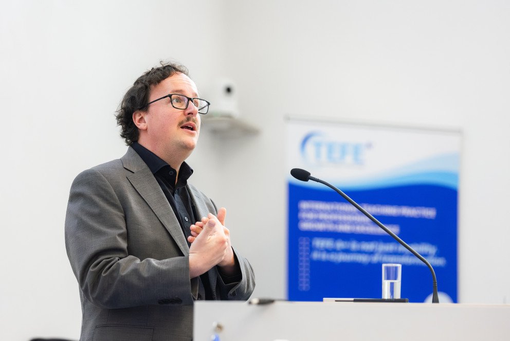 Dr. Jonas Scharfenberg von der Universit&auml;t Passau h&auml;lt am Rednerpult seinen Vortrag
