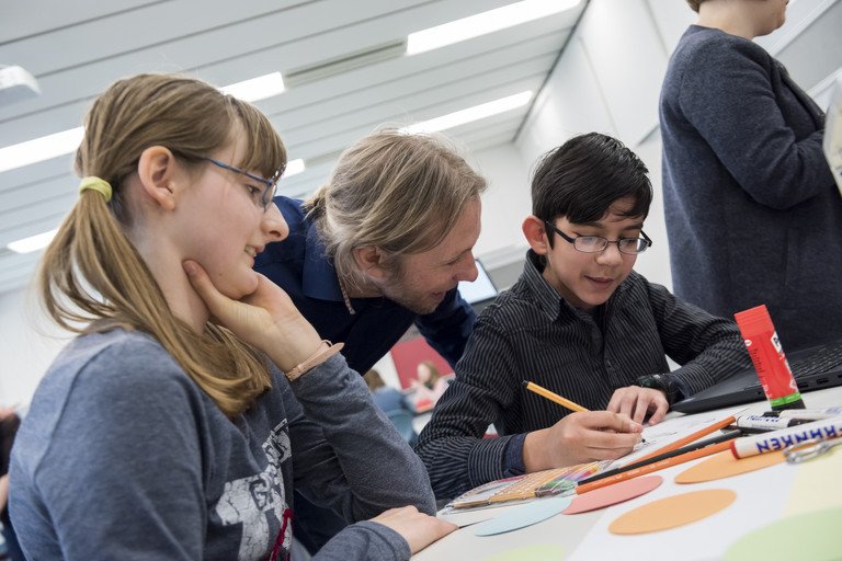 Ein paar Schler besichtigen das DiLab der Universitt Passau. Sie bearbeiten gerade Aufgaben an einem Tisch.