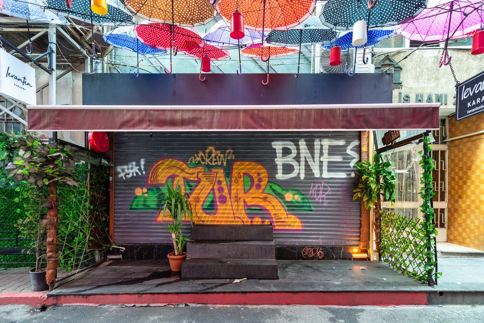 Zu sehen ist eine bunt graffitierte Ladenfront mit verschiedensten Schriftz&uuml;gen, wovon einer "BNE?" liest.