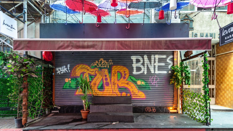 Zu sehen ist eine bunt graffitierte Ladenfront mit verschiedensten Schriftz&uuml;gen, wovon einer "BNE?" ist.