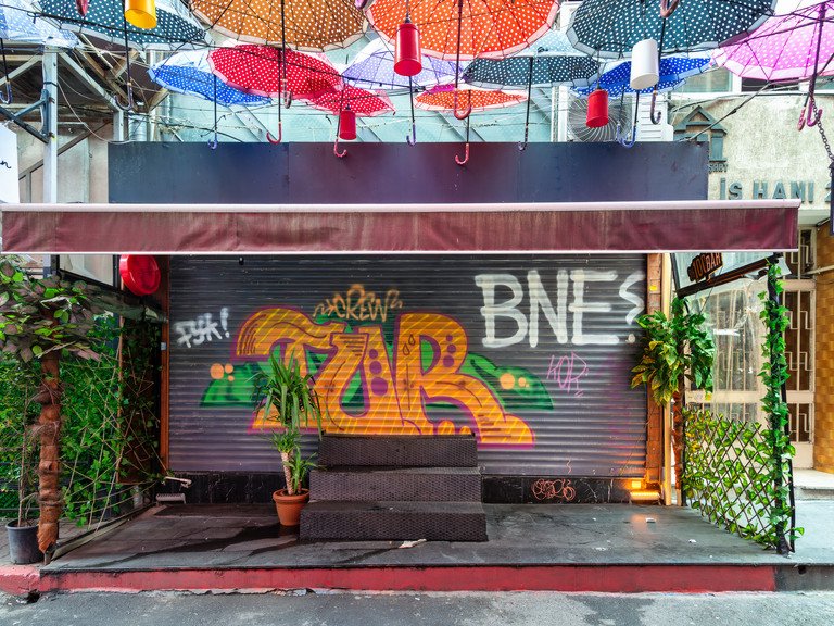 Zu sehen ist eine bunt graffitierte Ladenfront mit verschiedensten Schriftz&uuml;gen, wovon einer "BNE?" liest.
