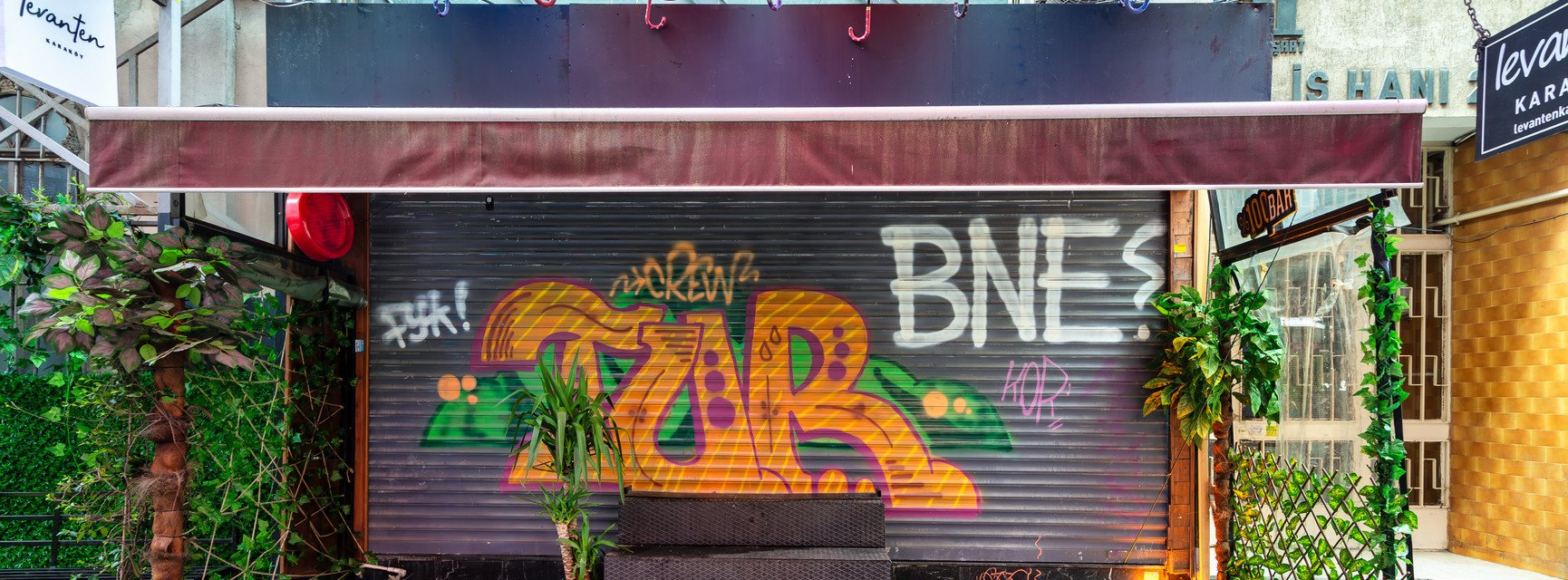 Eine bunte Ladenfront in Istanbul, T&uuml;rkei. Ein Graffiti auf der verschlossenen Ladenfront liest "BNE?".