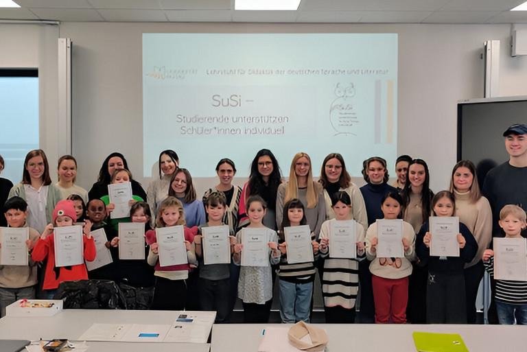 Die Schülerinnen und Schüler, die am Projekt SuSi teilgenommen haben, halten beim Gruppenfoto stolz ihre Urkunden in die Kamera.
